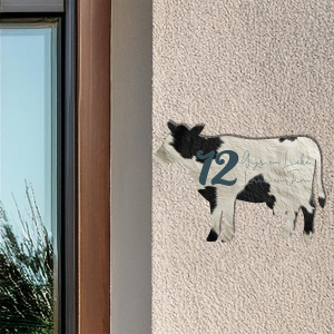 Naambordje in de vorm van een koe op houten deur
